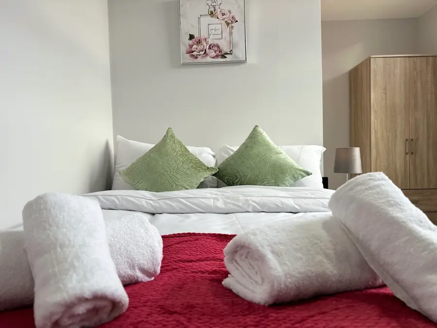 A freshly made bed with clean linen and rolled towels ready for arrival