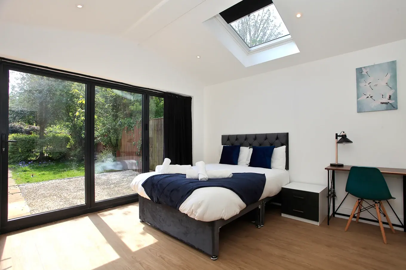 A bright double room with garden doors, a skylight and a work desk
