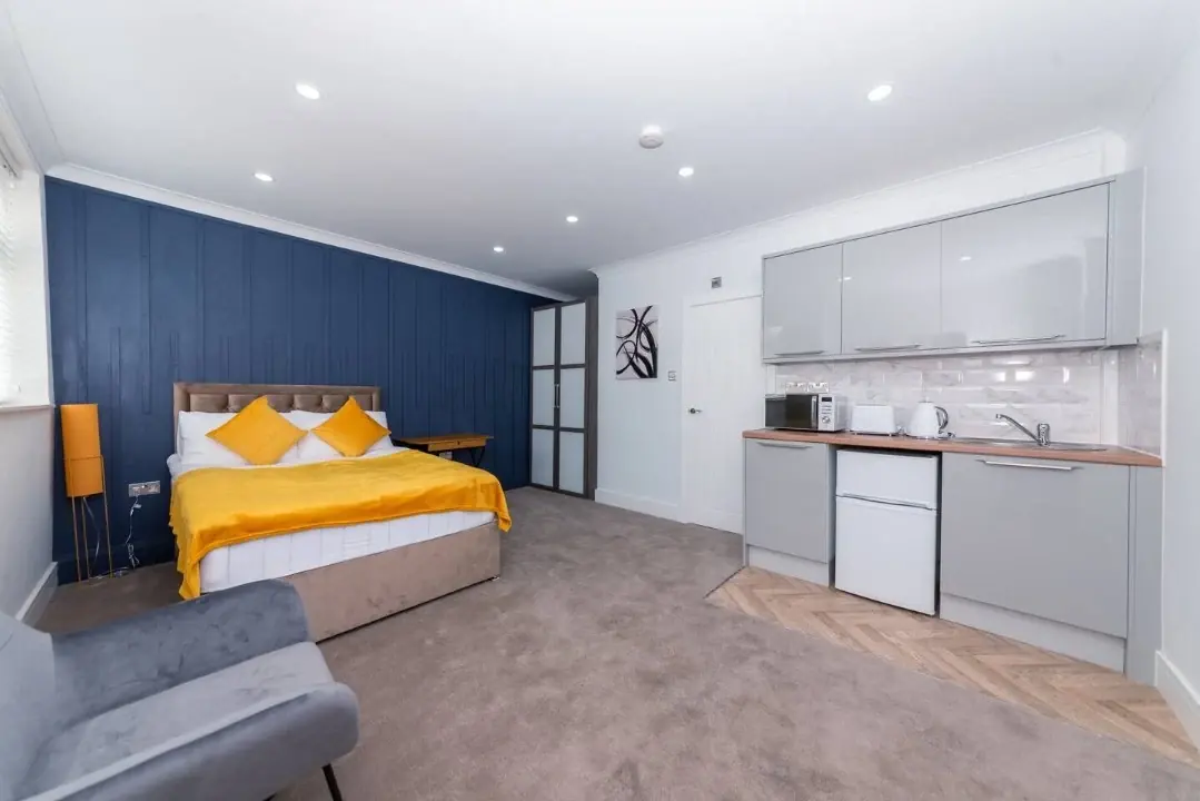 A studio apartment with a double bed, sofa and fitted kitchenette, suitable for a longer stay